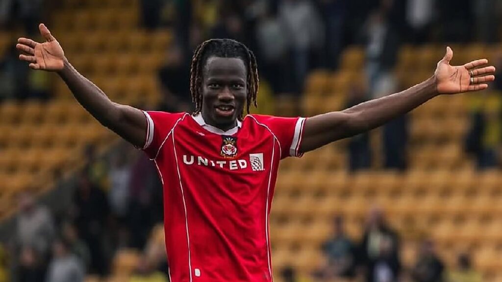 Issa Kaboré de braços abertos comemorando com a camisa do Wrexham