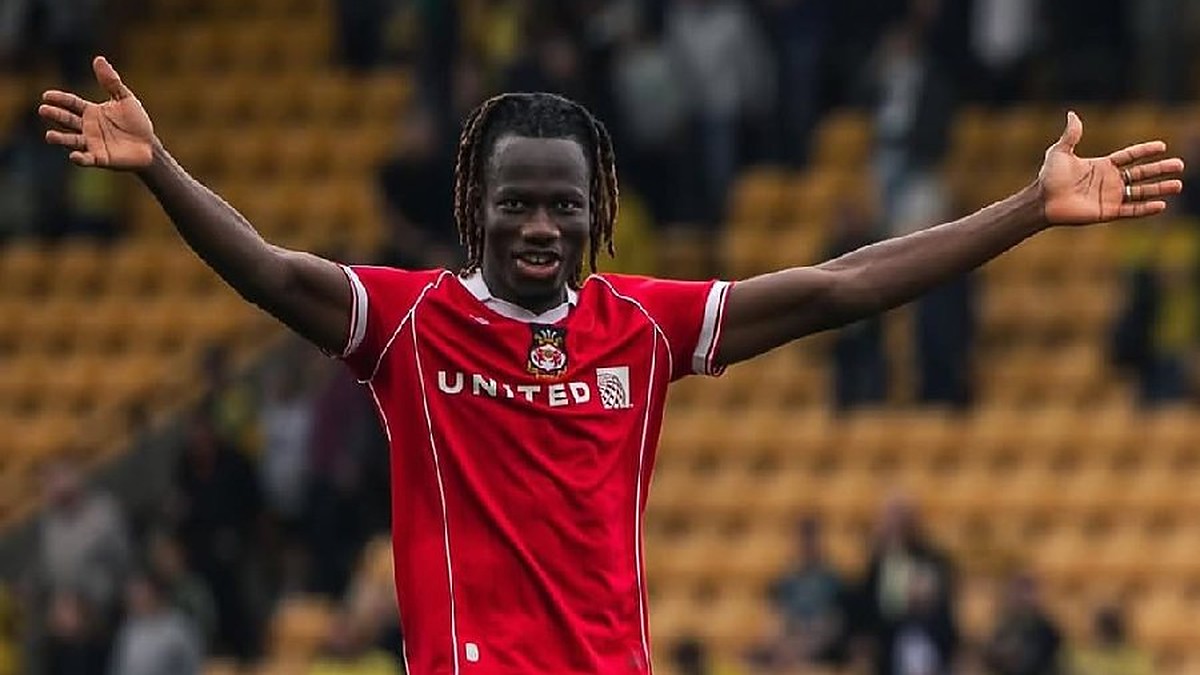 Issa Kaboré de braços abertos comemorando com a camisa do Wrexham